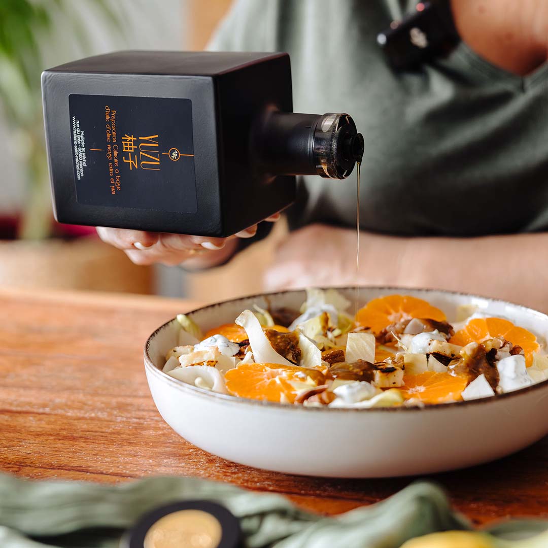 Salade de fenouil, orange et halloumi grillé nappée d'huile d'olive au yuzu, dressée dans une assiette blanche